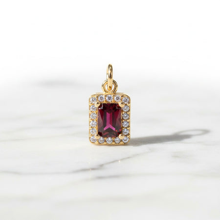 Gold pendant with a red gemstone on a white background