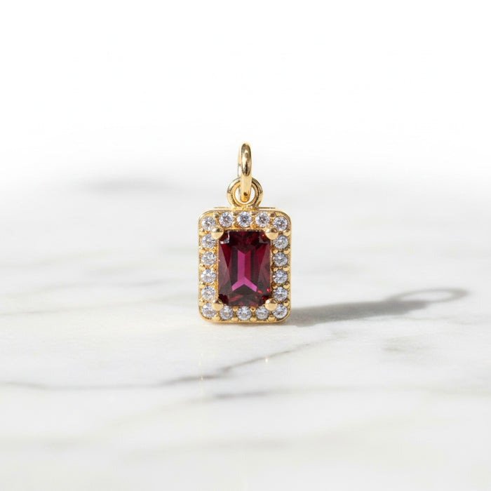 Gold pendant with a red gemstone on a white background