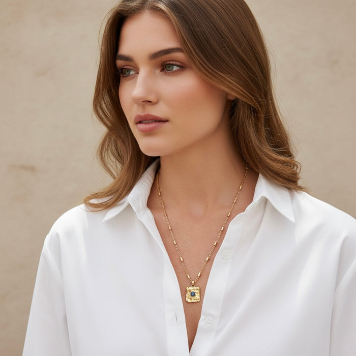 Woman wearing a white shirt and gold necklace with a beige background