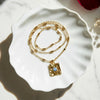 Gold necklace with a pendant on a white ceramic dish