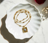 Gold necklace with a pendant on a white ceramic dish