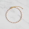 Gold and white enamel anklet on a marble surface