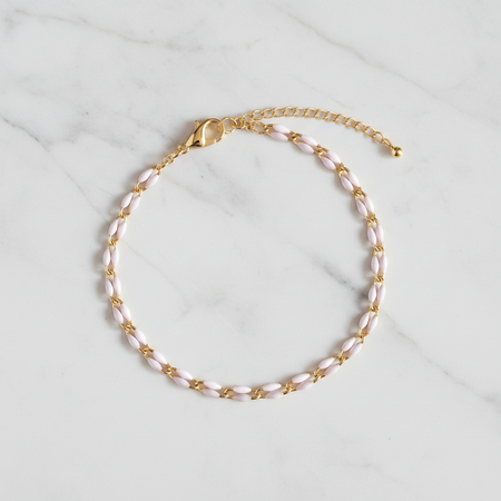 Gold and white enamel anklet on a marble surface