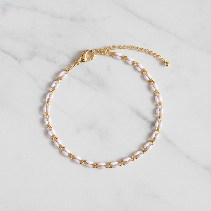 Gold and white enamel anklet on a marble surface