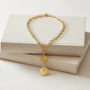 Gold bracelet with pendants on a white surface