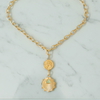 Gold chain necklace with pendant on a marble surface