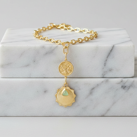 Gold bracelet with a pendant on a marble surface