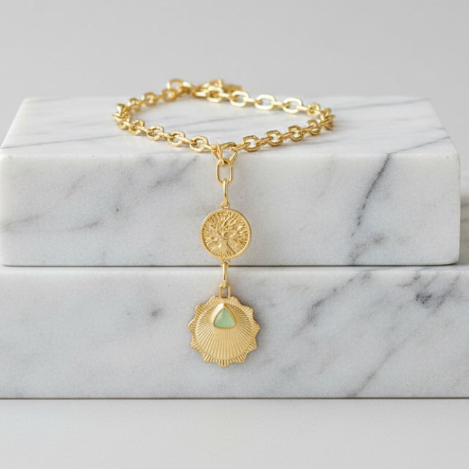 Gold bracelet with a pendant on a marble surface