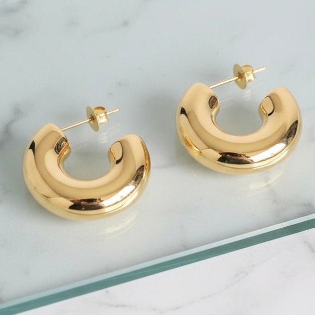 Gold hoop earrings on a marble surface
