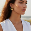 Woman wearing gold hoop earrings with a blurred natural background