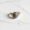 Gold ring with a blue stone on a marble surface