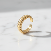 Gold ring with a ribbed design on a light gray background