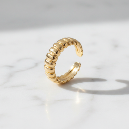 Gold ring with a ribbed design on a light gray background