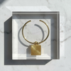 Gold necklace with a square pendant on a marble surface