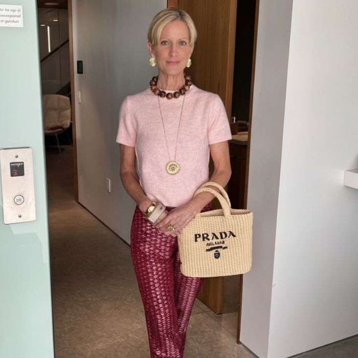 Woman holding a Prada handbag  and gold stud earrings in an indoor setting