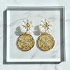 Gold and white floral earrings on a marble surface