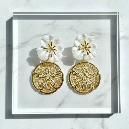 Gold and white floral earrings on a marble surface