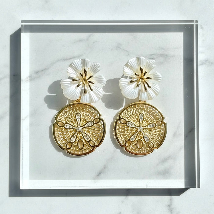 Gold and white floral earrings on a marble surface