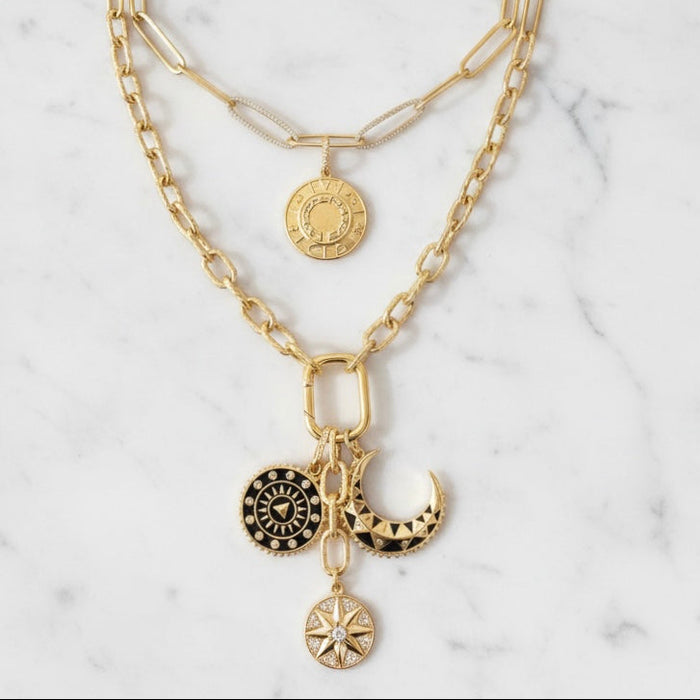 Gold chain necklace with various charms on a marble background