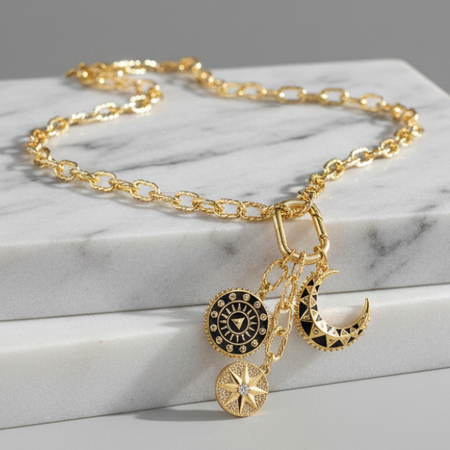 Gold necklace with charms on a marble surface