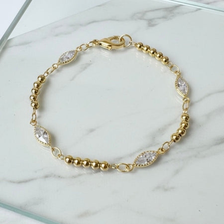 Gold bracelet with clear stones on a marble surface