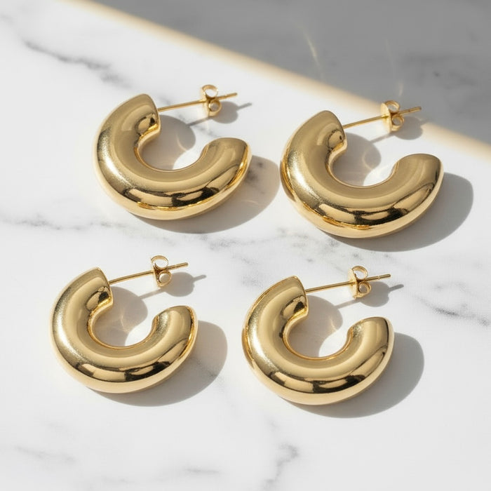 Gold hoop earrings on a marble surface
