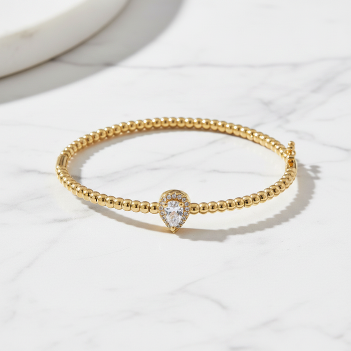 Gold bracelet with a heart-shaped diamond on a white surface