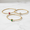 Three gold bracelets with gemstones on a white background