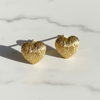 Gold heart-shaped earrings on a light marble background