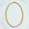 Gold chain necklace on a white marble surface