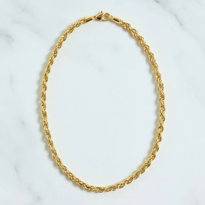 Gold chain necklace on a white marble surface