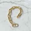 Gold chain bracelet with a heart-shaped charm on a marble surface