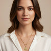 Woman wearing a gold necklace against a beige background