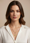 Woman wearing a gold necklace against a beige background