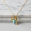 Necklace with charms including a fish, starfish, and shell on a marble background
