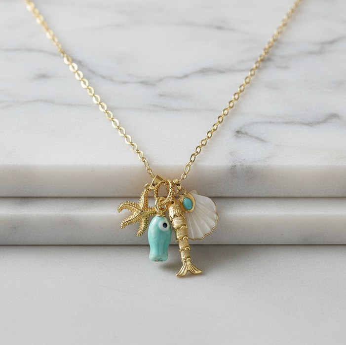 Necklace with charms including a fish, starfish, and shell on a marble background