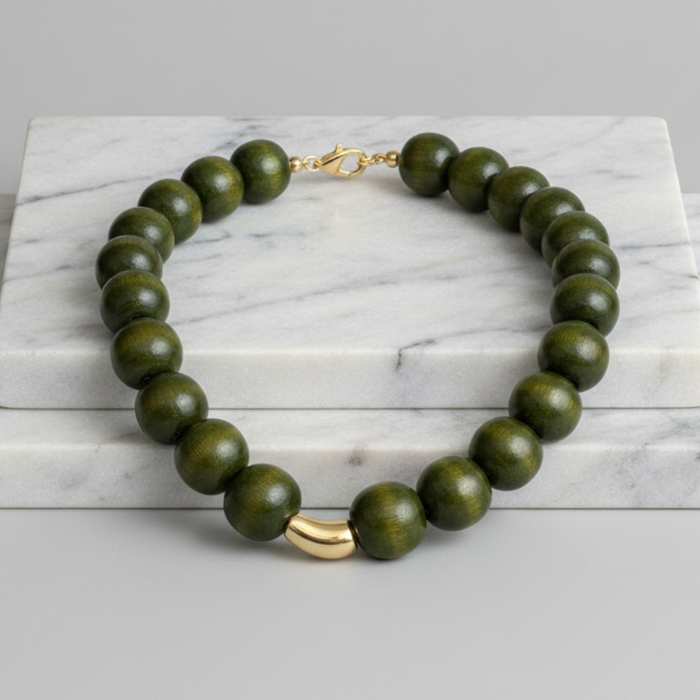 Green beaded necklace with gold clasp on a marble surface