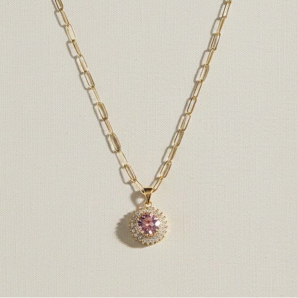 Gold necklace with a pink pendant on a beige book