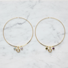 A pair of necklaces with small dangling charm beads, displayed on a white marble surface.