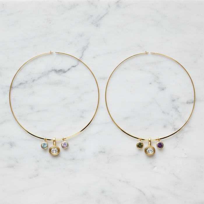 A pair of necklaces with small dangling charm beads, displayed on a white marble surface.