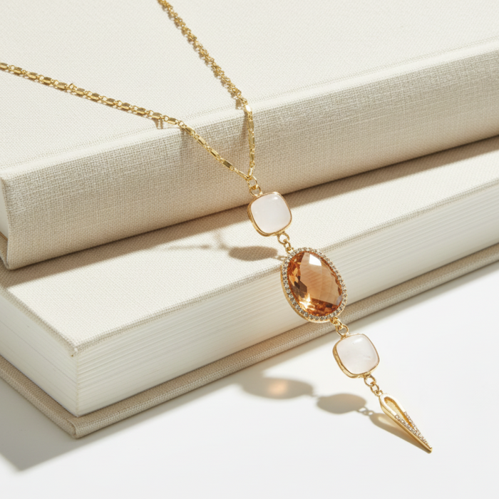 Gold necklace with a peach-colored pendant on a white surface