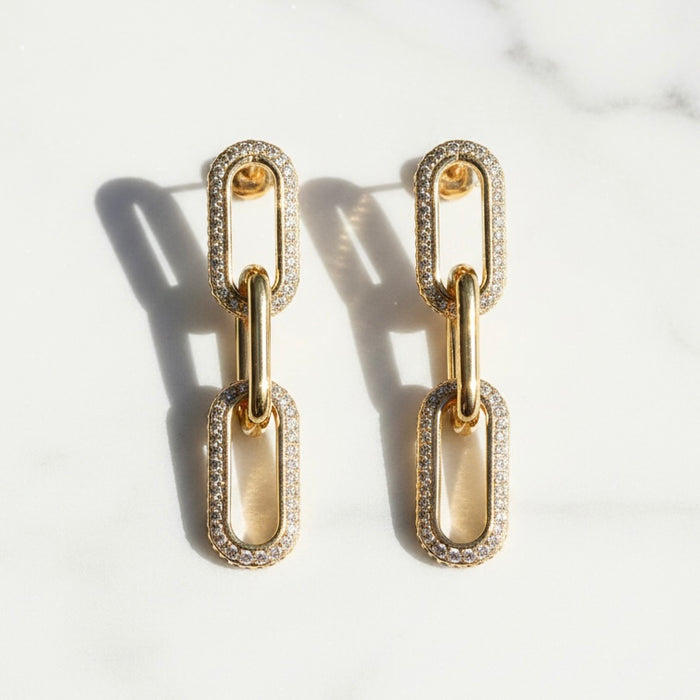 Gold chain-link earrings with diamond accents on a light background