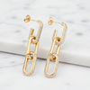 Gold chain-link earrings on a marble surface