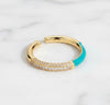 Gold and turquoise ring with gemstones on a light gray background
