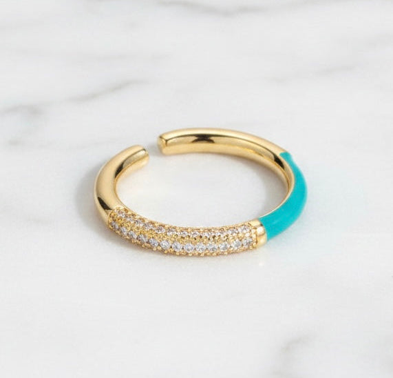 Gold and turquoise ring with gemstones on a light gray background
