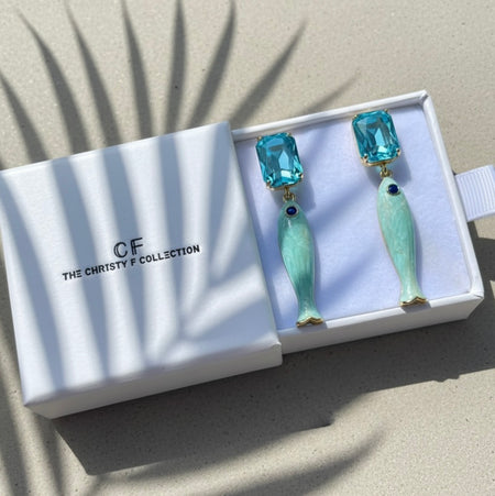 Pair of fish-shaped earrings with blue gemstones in a 'The Christy F Collection' box.