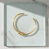 Gold bracelet on a white marble surface