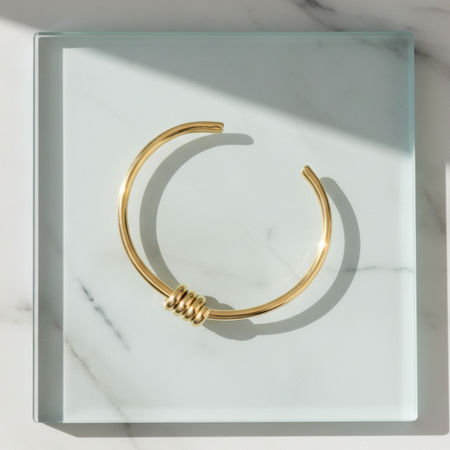 Gold bracelet on a white marble surface
