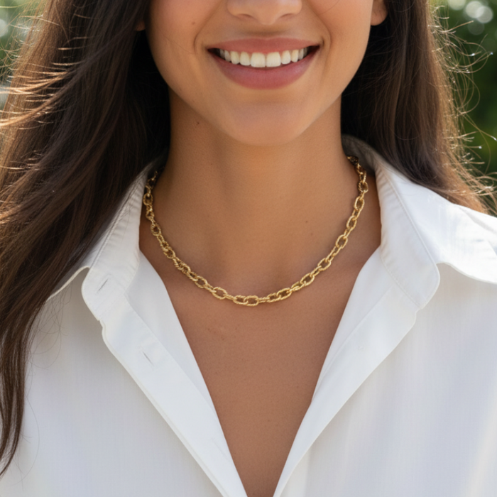 Woman wearing a gold chain necklace with a blurred green background