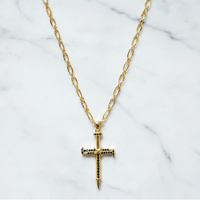 Gold cross necklace on a marble background